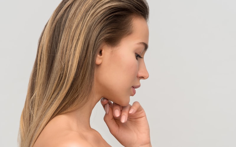A client in profile with clear, healthy skin, resting a hand at her jaw