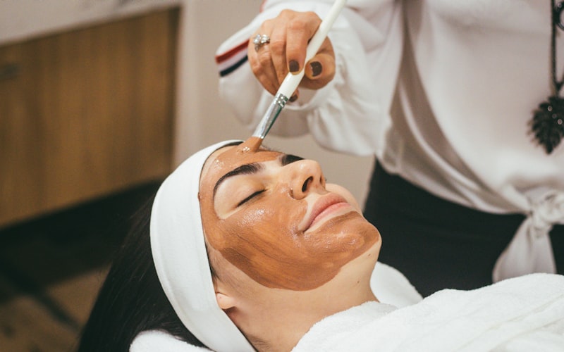 A treatment mask being brushed onto a client's face during a facial