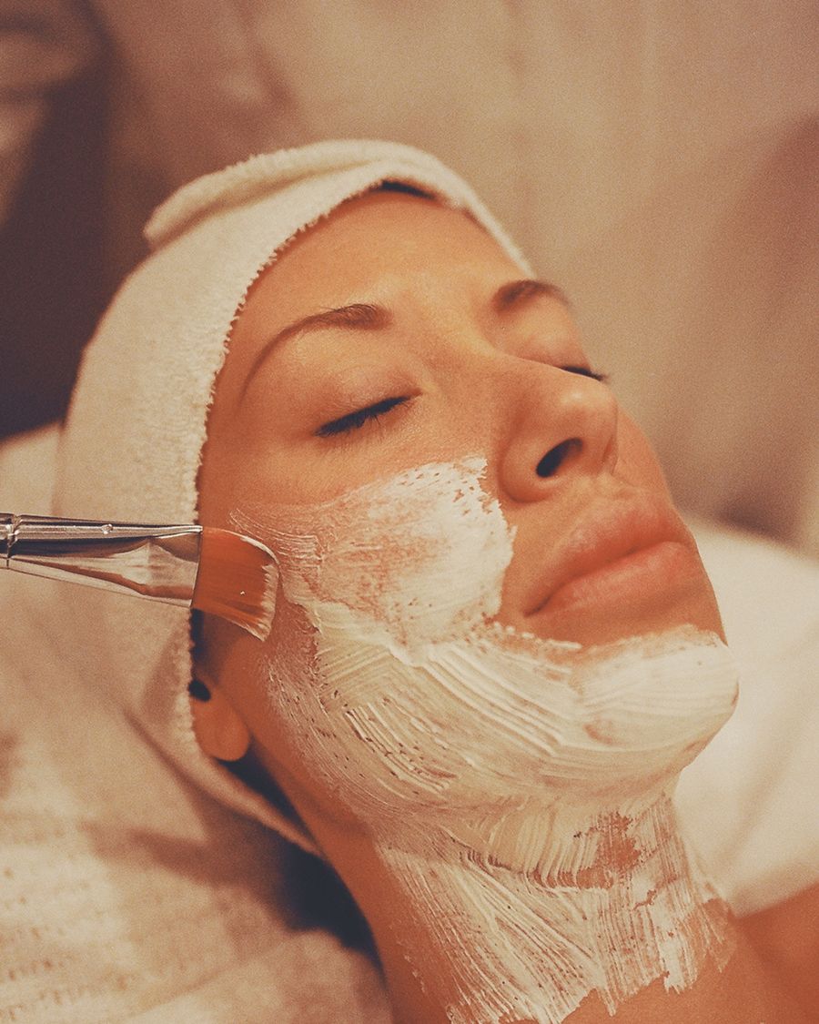 A treatment mask being applied slowly and carefully to a client's face during a facial